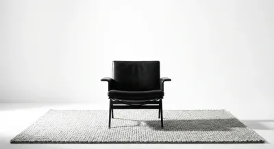 Fauteuil design noir sur tapis gris dans un salon minimaliste