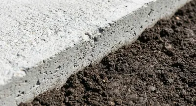 Détail structurel d'une bêche de dallage en béton montrant l'ancrage dans le sol.