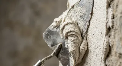 Gros plan d'une lisseuse étalant de l'enduit à la chaux blanc