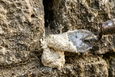 Application du mortier de chaux entre deux pierres avec une truelle langue de chat
