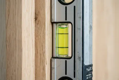 Gros plan sur un niveau à bulle vérifiant la verticalité d'une huisserie de porte